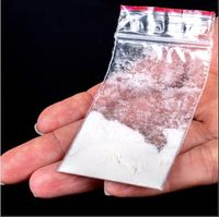 A close-up of a small, clear, plastic bag containing fentanyl in someone's hand.