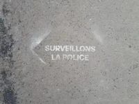 Spray paint on pavement that says surveillons la police.