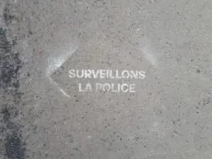 Spray paint on pavement that says surveillons la police.