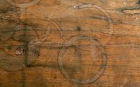A wood tabletop is pictured with circular water stains.