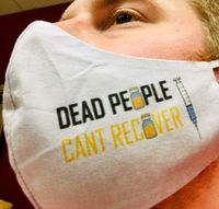 A close-up of a man's face shown wearing a mask that says "Dead people can't recover". &rdquo;