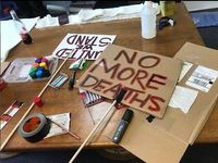 Home-made protest signs on a table that read 'no more deaths'.