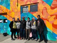 The Dr. Peter team posing in front of a wall painted with a mural in Victoria, BC.
